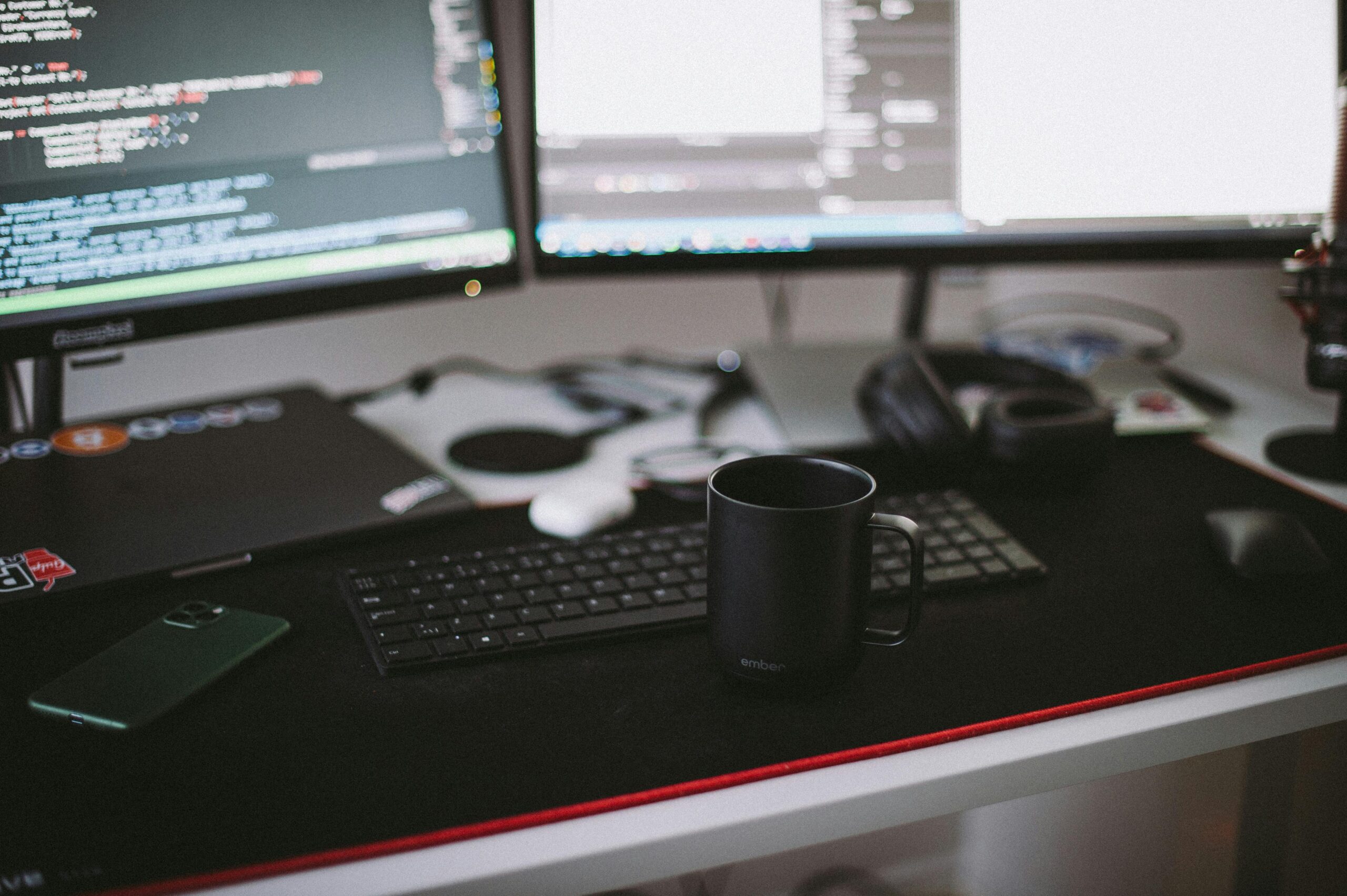 Cozy home office setup featuring dual monitors, a keyboard, and a black ceramic mug.
